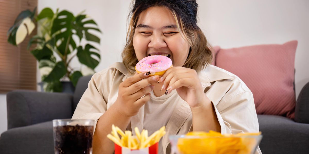 happy-asian-fat-woman-enjoy-eating-delicious-sweet-donut-fast-food-living-room-min