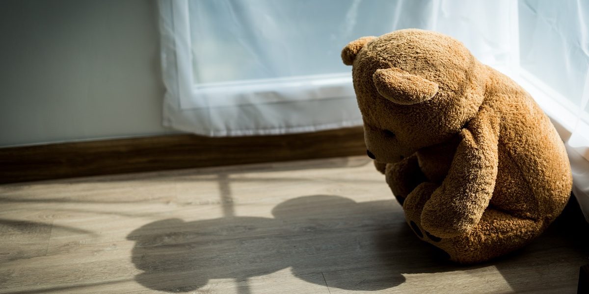 The teddy bear looks sad and disappointed in the corner of the room with soft sunlight passing through. Dolls with depression or mental illness. Childhood illness or sickness concept